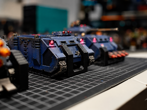 Armoured vehicle miniatures lined up in magnetic holders on a workbench