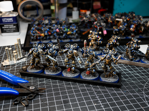 Magnetic infantry trays, magnets and nippers laid out on a hobby workbench