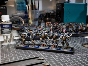 Painted infantry miniatures stored on a magnetic rack at a hobby workbench