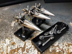Spare weapons in a bitz box beside a flight stand tray of jetbike miniatures